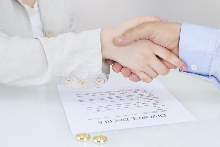 couple shaking hands after signing divorce papers