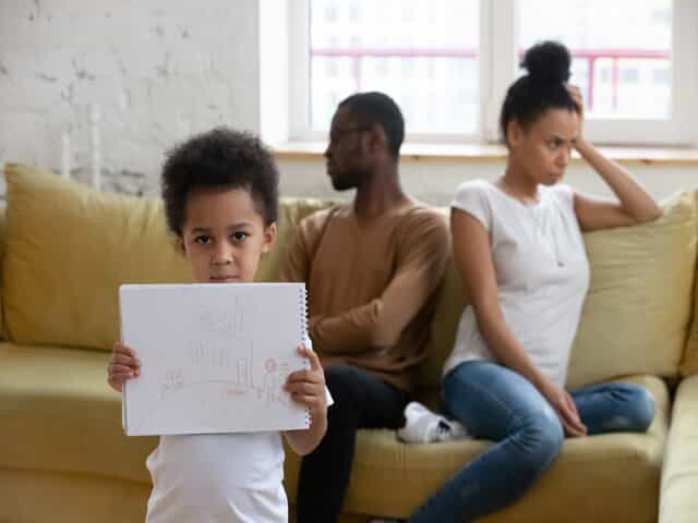 Children Holding Up Picture in Front of Fighting Parents