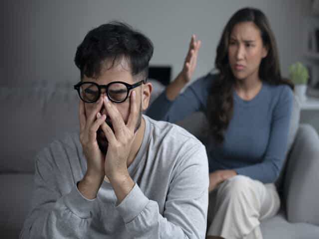 Man Covering Face with Hands While Woman Complains