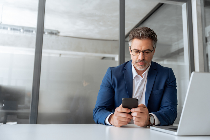 man in a suit typing on his phone in a conference room