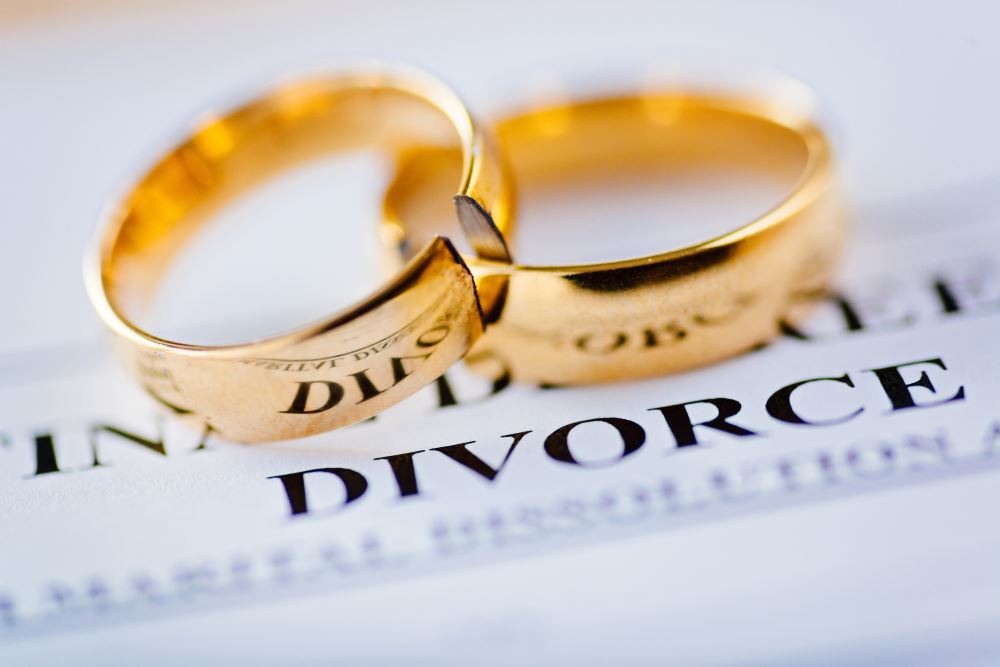 Two broken golden wedding rings divorce decree document.