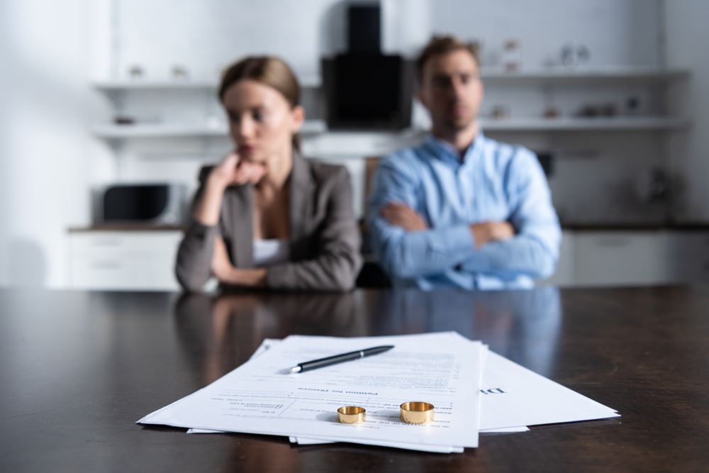 couple with divorce paperwork and marriage rings on table