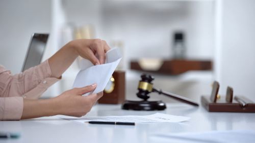 woman reaching into envelope at law office